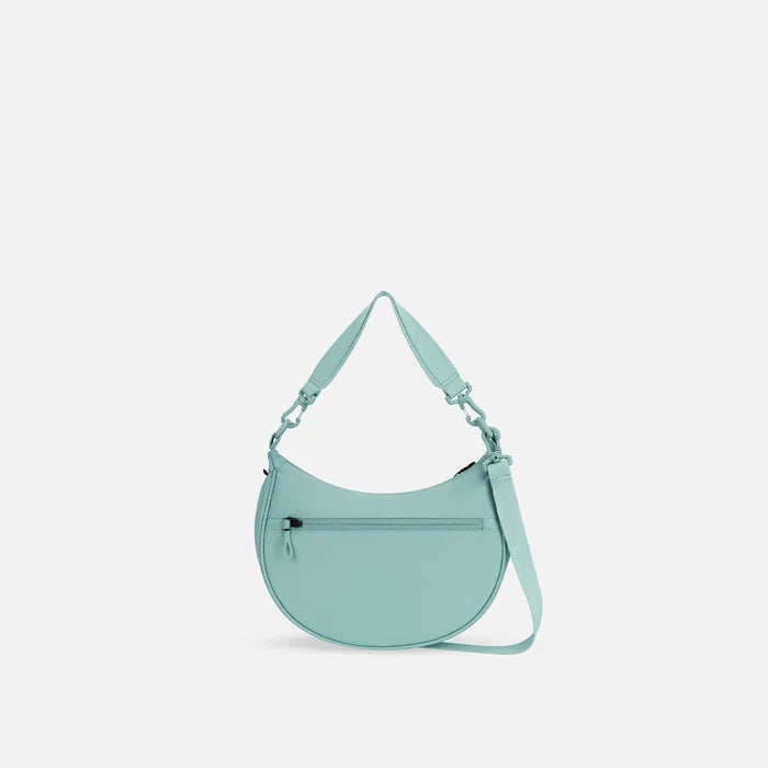 A Sherpani Mina Surf Blue Medium Crossbody Bag, back view showing straps and lockable pocket on white background.  #color_surf-blue