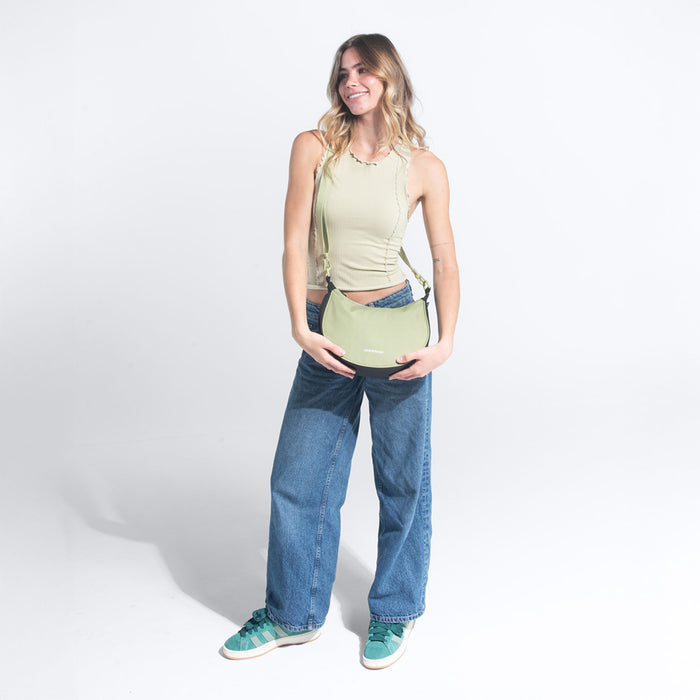 Woman wearing a Sherpani Mina Palm Green Medium Crossbody Bag against white background.  #color_palm-green
