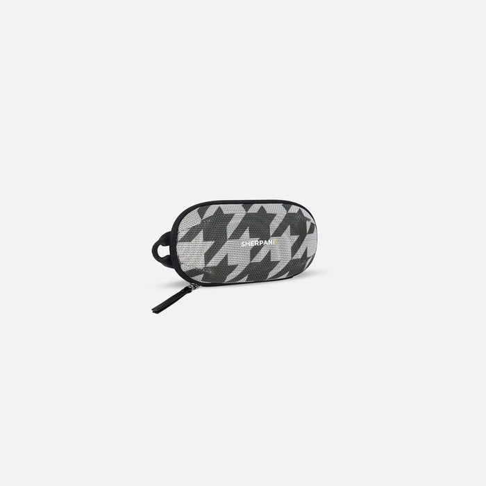 A Sherpani Mini Co-Pilot Houndstooth Mini Travel Organizer, 3/4 view showing main zipper and side handle on white background.  #color_houndstooth-print