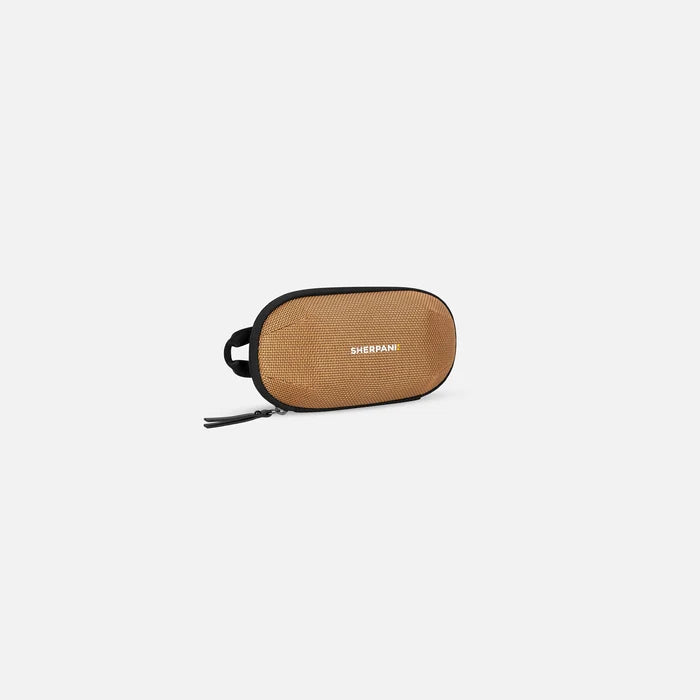 A Sherpani Mini Co-Pilot Sand Mini Travel Organizer, 3/4 view showing main zipper and side handle on white background.  #color_sand-tan