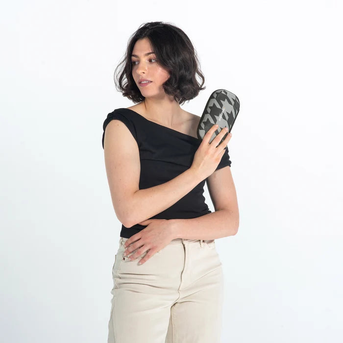 Woman holding a Sherpani Mini Co-Pilot Houndstooth Mini Travel Organizer against white backdrop. #color_houndstooth-print