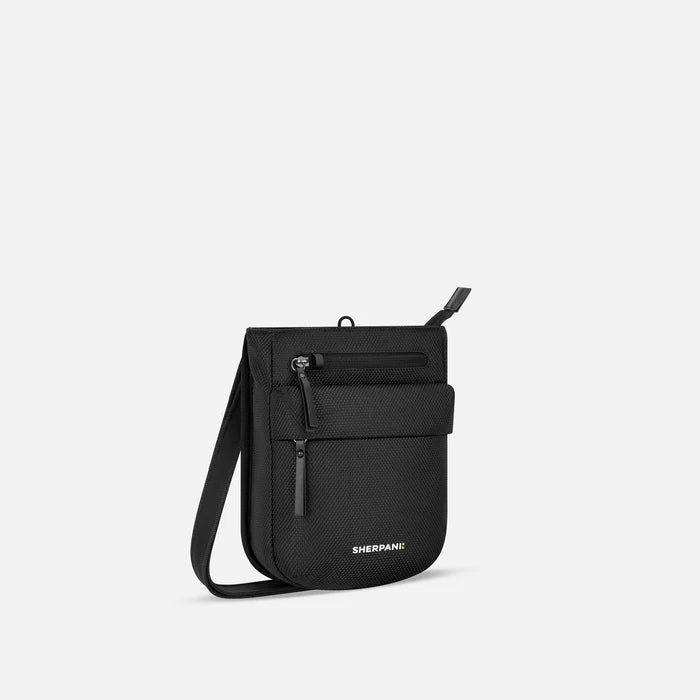 A Sherpani Prima Carbon Black Anti-theft Travel Crossbody, 3/4 view showing lockable pocket and strap on white background. #color_carbon-black