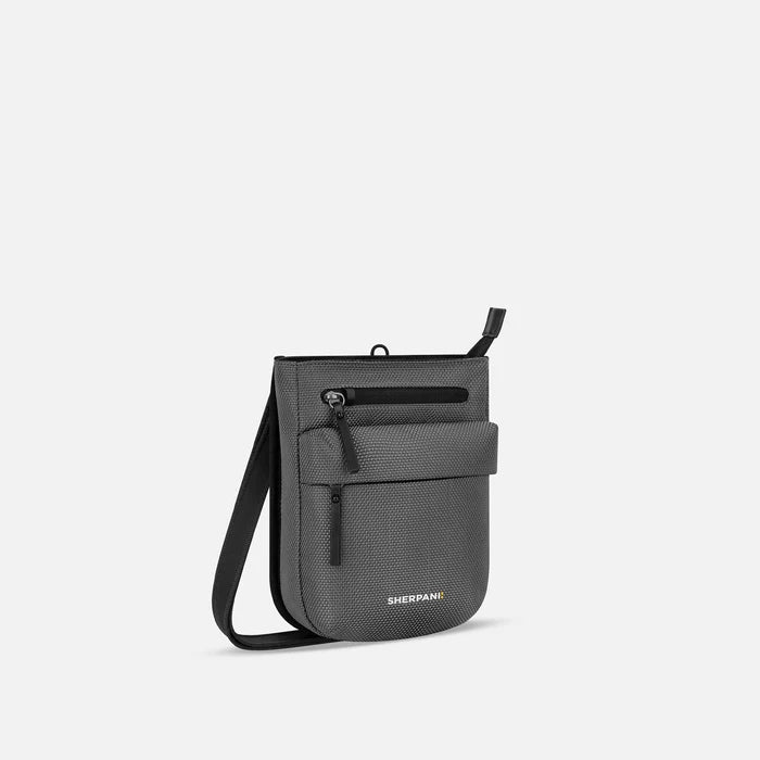 A Sherpani Prima Granite Anti-theft Travel Crossbody, 3/4 view showing lockable pocket and strap on white background. #color_granite-grey