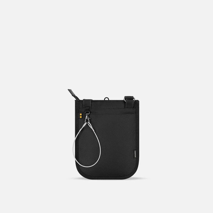 A Sherpani Prima Granite Anti-theft Travel Crossbody, back view showing black backside & chair lock on white backdrop. #color_granite-grey