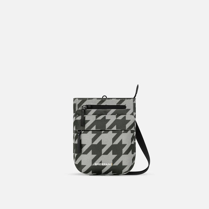 A Sherpani Prima Houndstooth Anti-theft Travel Crossbody, front view showing lockable pocket and strap on white background. #color_houndstooth-print