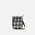 A Sherpani Prima Houndstooth Anti-theft Travel Crossbody, front view showing lockable pocket and strap on white background. #color_houndstooth-print