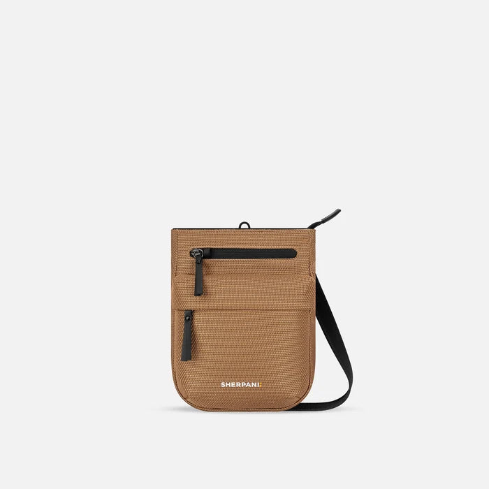 A Sherpani Prima Sand Anti-theft Travel Crossbody, front view showing lockable pocket and strap on white background. #color_sand-tan