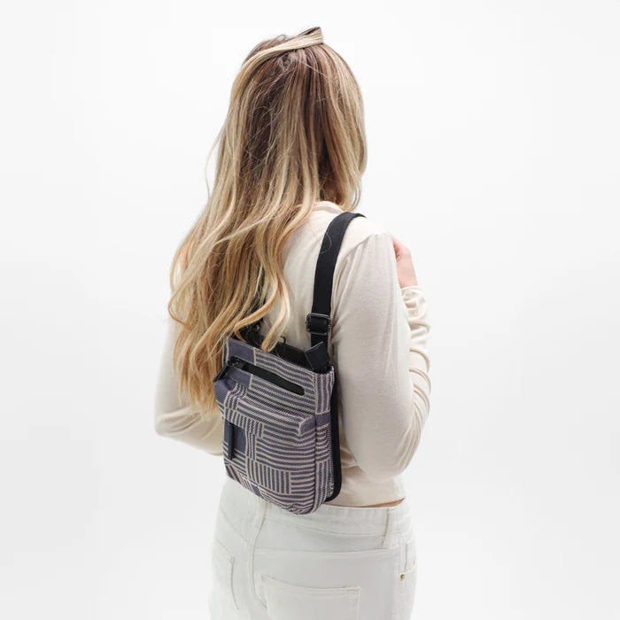 Woman wearing a Sherpani Prima Passport Anti-Theft Travel Crossbody over her shoulder against white background.  #color_passport-print