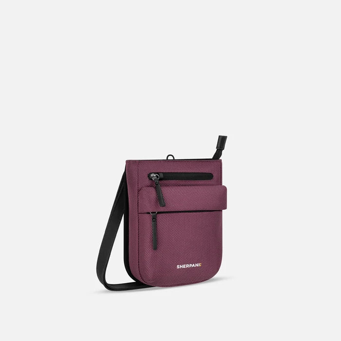 A Sherpani Prima Smoky Orchid Anti-theft Travel Crossbody, 3/4 view showing lockable pocket and strap on white background. #color_smoky-orchid-pink