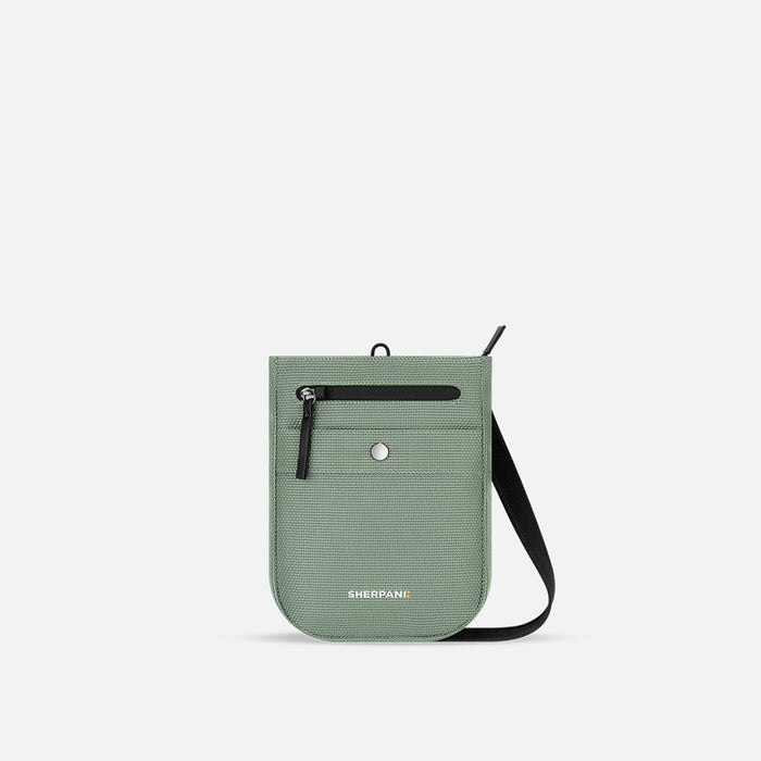 A Sherpani Prima Aloe Mist Green Anti-theft Travel Crossbody, front view showing lockable pocket and strap on white background. #color_aloe-mist-green
