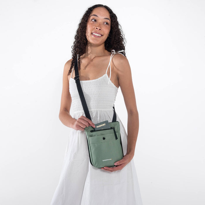Woman wearing a Sherpani Prima Aloe Mist Green Travel Crossbody on her shoulder against white background. #color_aloe-mist-green