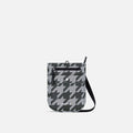 A Sherpani Prima Granite Grey Anti-theft Travel Crossbody, front view showing lockable pocket and strap on a white background. #color_houndstooth-print