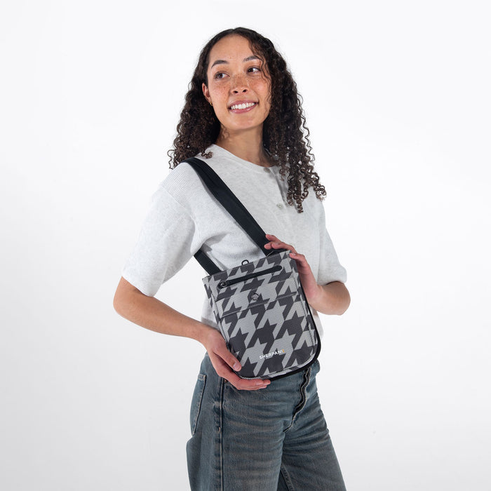 Woman wearing a Sherpani Prima Houndstooth Travel Crossbody on her shoulder against white background.  #color_houndstooth-print