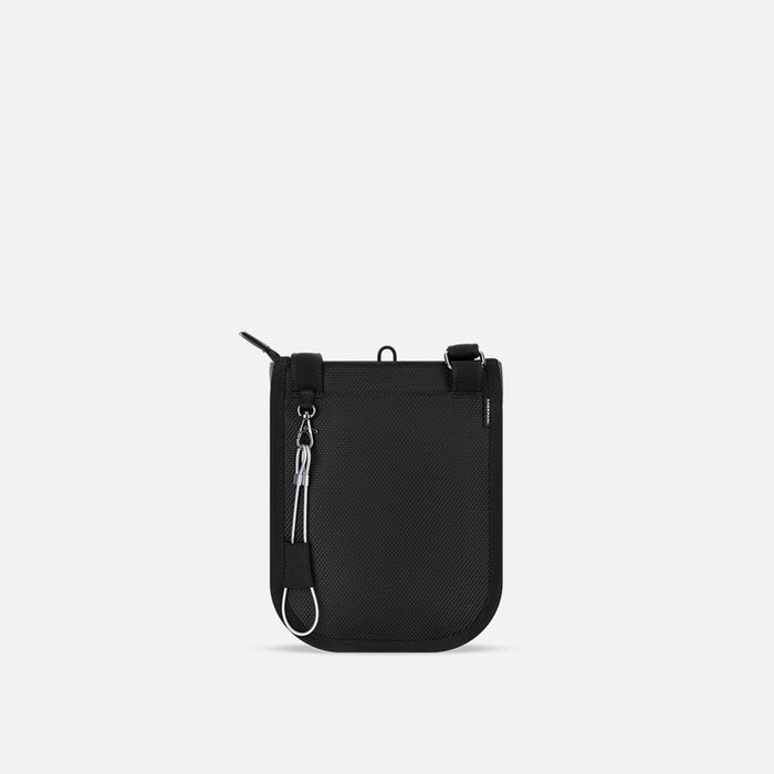 A Sherpani Prima Houndstooth Anti-theft Travel Crossbody, back view showing black backside & chair lock on white backdrop. #color_houndstooth-print
