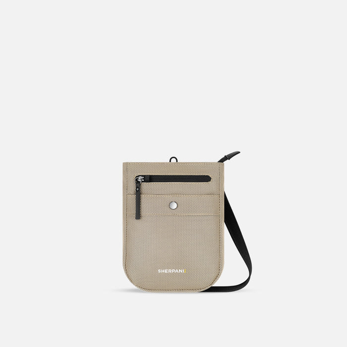 A Sherpani Prima Straw Beige Anti-theft Travel Crossbody, front view showing lockable pocket and strap on a white background. #color_straw-beige
