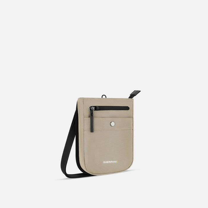 A Sherpani Prima Straw Beige Anti-theft Travel Crossbody, 3/4 view showing lockable pocket and strap on a white background. #color_straw-beige