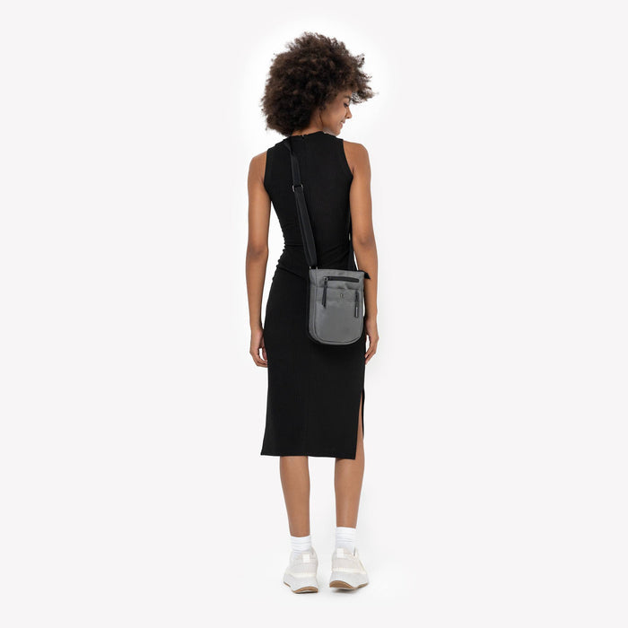 Woman wearing a Sherpani Prima Granite Travel Crossbody on her shoulder against white background. #color_granite