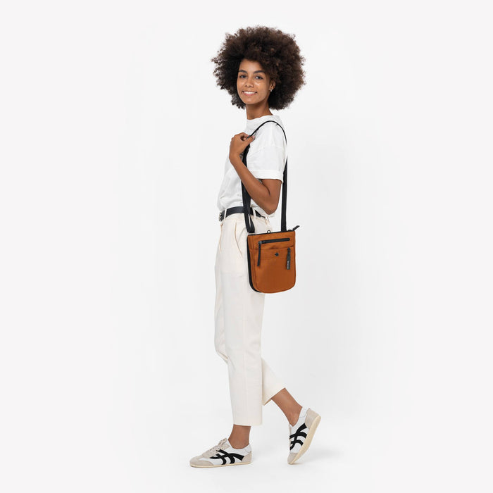 Woman wearing a Sherpani Prima Morocco Travel Crossbody on her shoulder against white background. #color_morocco