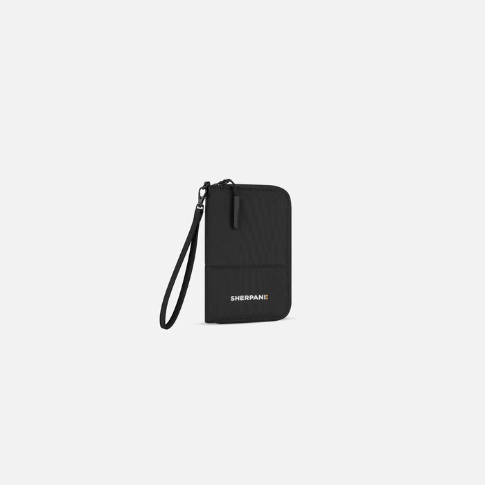 A Sherpani Rio Black Passport Wallet, 3/4 view showing wrist strap on white backdrop.  #color_black