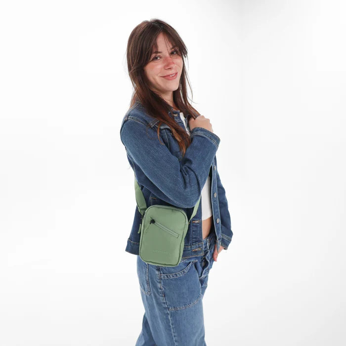 Woman wearing a Sherpani Rogue Olivine Mini Crossbody on her shoulder against white background.   #color_olivine-green