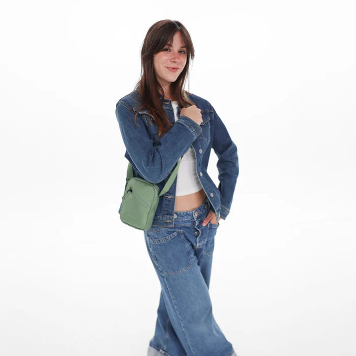 Woman wearing a Sherpani Rogue Olivine Mini Crossbody on her shoulder against white background.   #color_olivine-green