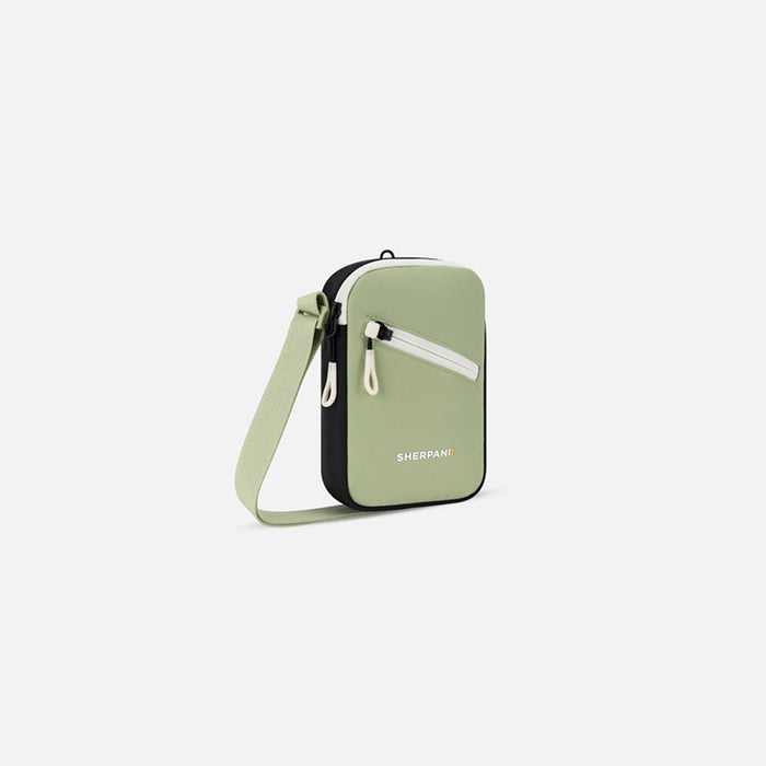 A Sherpani Rogue Palm Green Mini Crossbody, 3/4 view showing lockable pocket & strap on white backdrop. #color_palm-green