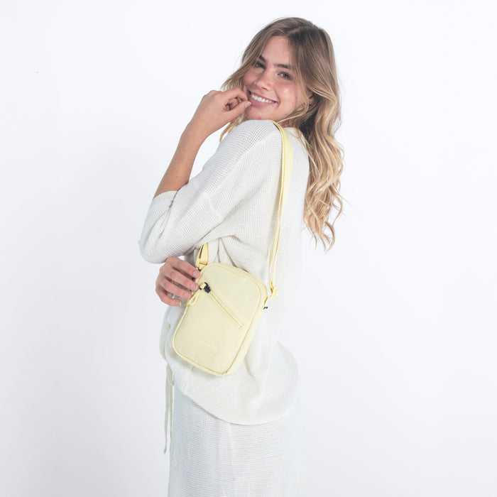 Woman wearing a Sherpani Rogue Sol Yellow Mini Crossbody on her shoulder against white background. #color_sol-yellow
