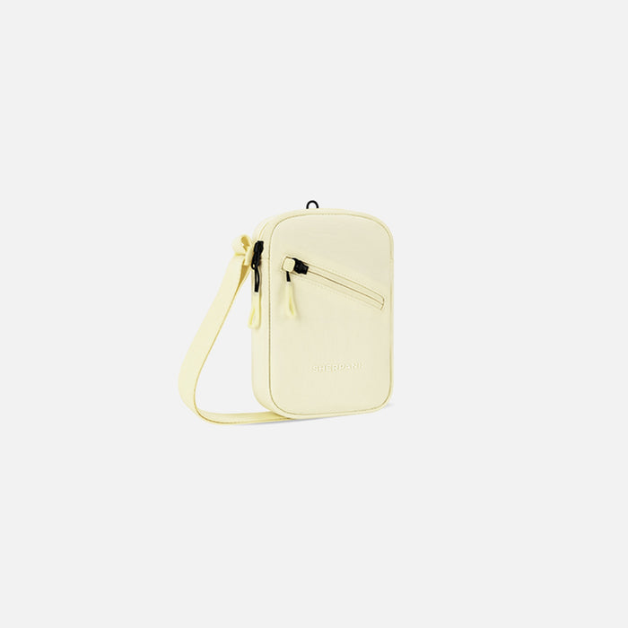 A Sherpani Rogue Sol Yellow Mini Crossbody, 3/4 view showing lockable pocket & strap on white backdrop. #color_sol-yellow