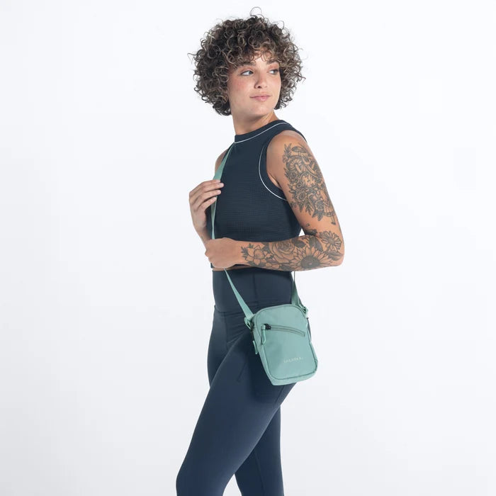 Woman wearing a Sherpani Rogue Surf Blue Mini Crossbody on her shoulder against white background.   #color_surf-blue