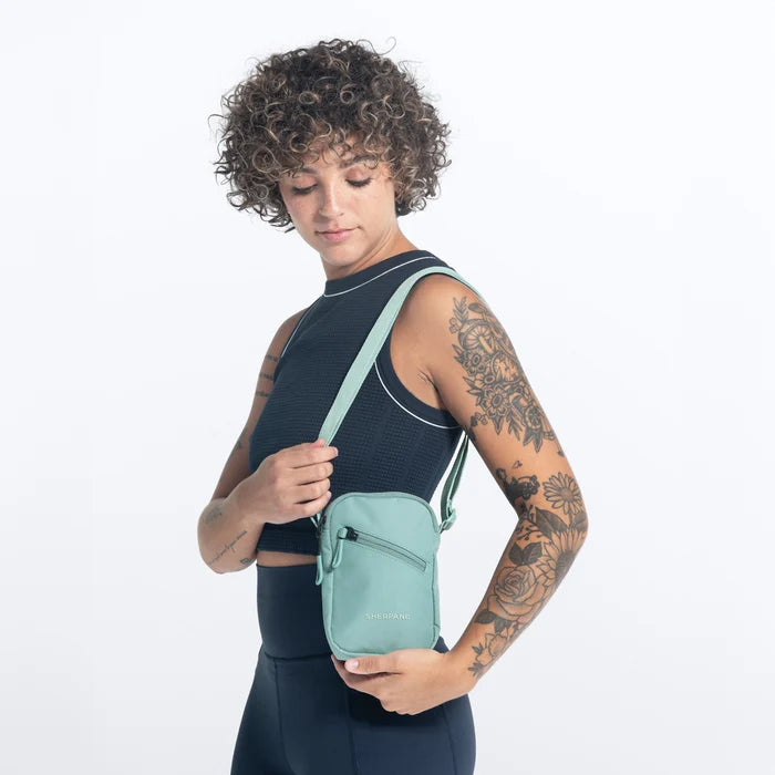 Woman wearing a Sherpani Rogue Surf Blue Mini Crossbody on her shoulder against white background.   #color_surf-blue