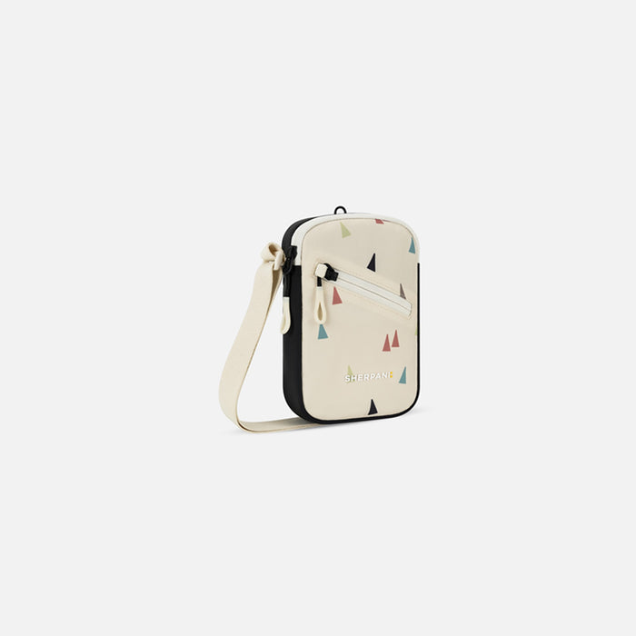 A Sherpani Rogue Terrazzo Print Mini Crossbody, 3/4 view showing lockable pocket & strap on white backdrop. #color_terrazzo-print