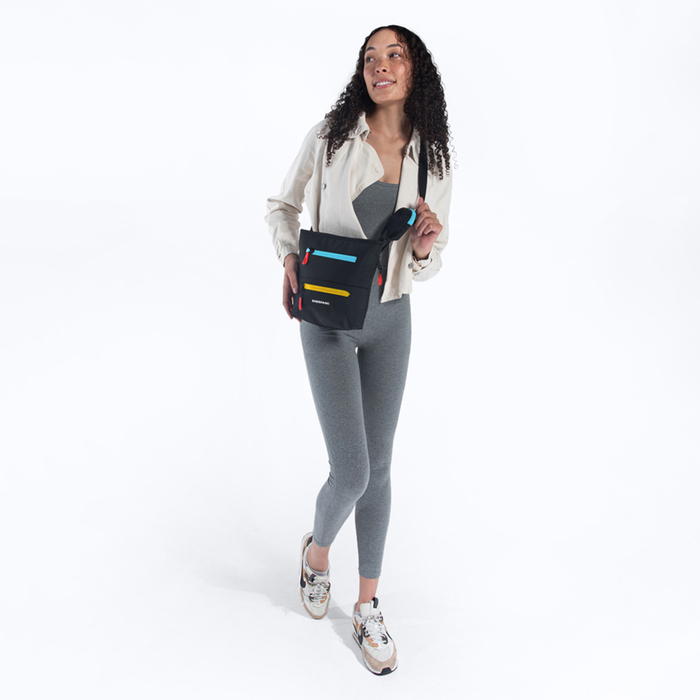 A woman wearing a Sherpani Sadie Chromatic Black Crossbody Bag against a white background.  #color_chromatic-black