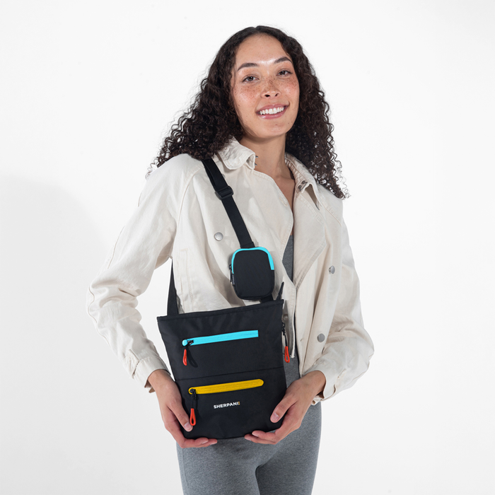 A woman wearing a Sherpani Sadie Chromatic Black Crossbody Bag against a white background.  #color_chromatic-black