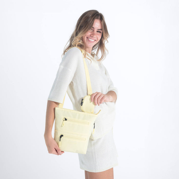 Woman wearing a Sherpani Sadie Sol Yellow Crossbody Bag on her shoulder against white backdrop. #color_sol-yellow