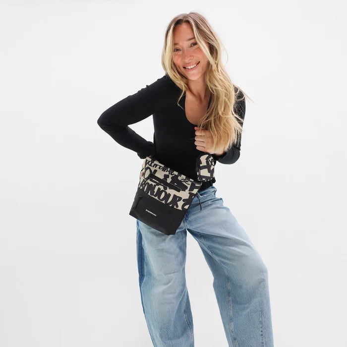 A woman wearing Sherpani Sadie Ciao Crossbody Bag against a white background.  #color_ciao-print