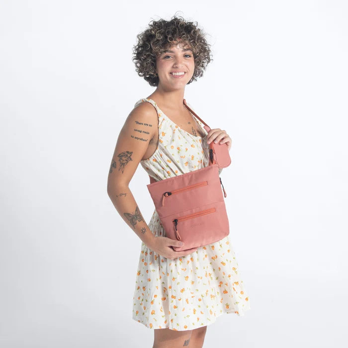 A woman wearing Sherpani Sadie Desert Pink Crossbody Bag against a white background.  #color_desert-pink