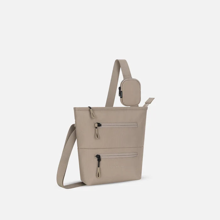 A Sherpani Dune Crossbody Bag, 3/4 view showing front lockable zipper pockets and the pouch attached to the strap. #color_dune-tan
