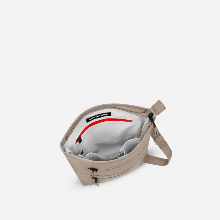 A Sherpani Sadie Dune Crossbody Bag, above view showing inside main pocket against white backdrop.    #color_dune-tan