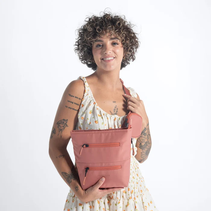 A woman wearing a Sherpani Sadie Desert Pink Crossbody Bag against a white background. #color_desert-pink