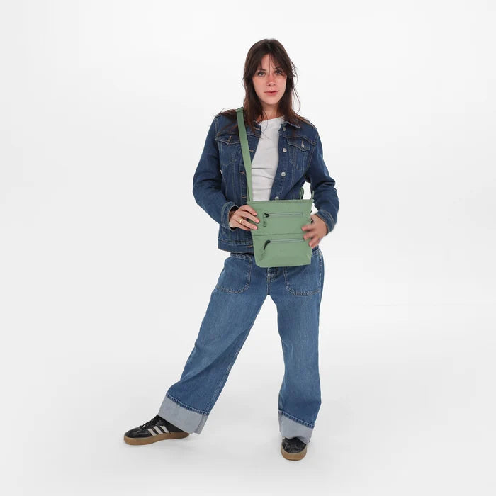A woman wearing a Sherpani Sadie Olivine Crossbody Bag against a white background. #color_olivine-green