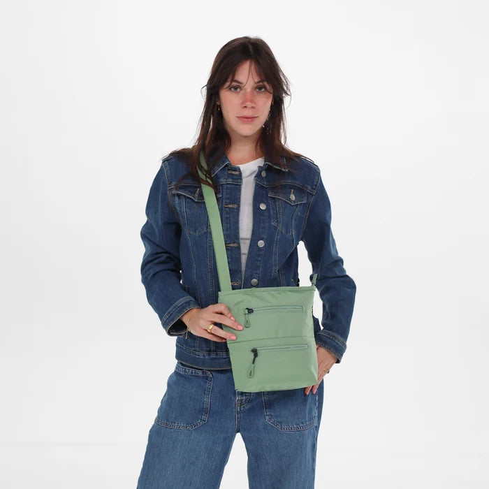 A woman wearing Sherpani Sadie Olivine Crossbody Bag against a white background.  #color_olivine-green