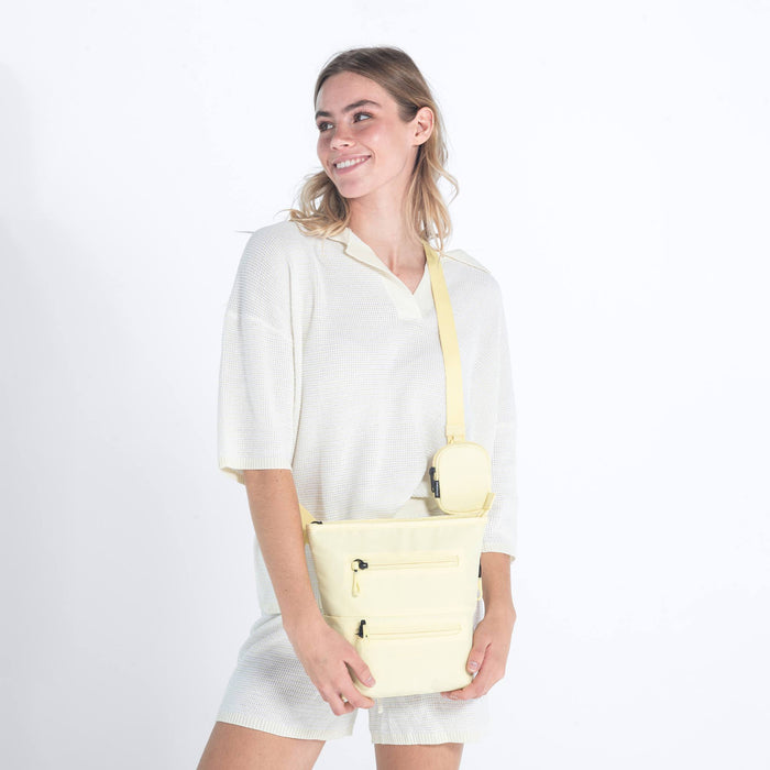 Woman wearing a Sherpani Sadie Sol Yellow Crossbody Bag against white backdrop. #color_sol-yellow