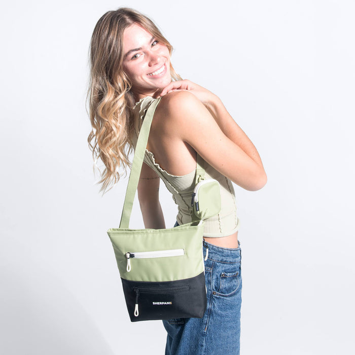 Woman wearing a Sherpani Sadie Palm Green Crossbody Bag on her shoulder against white backdrop. #color_palm-green