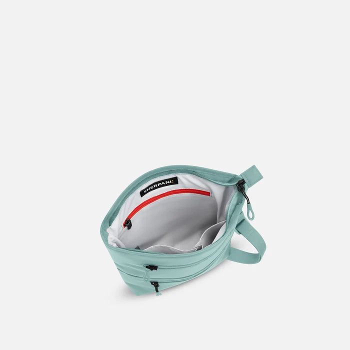 A Sherpani Sadie Surf Blue Crossbody Bag, above view showing inside main pocket against white backdrop.    #color_surf-blue