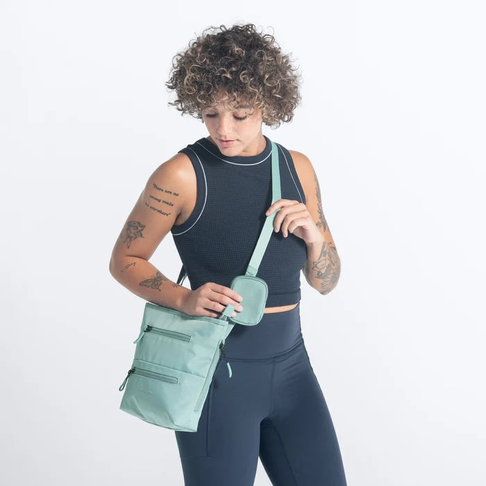 A woman wearing Sherpani Sadie Surf Blue Crossbody Bag against a white background.  #color_surf-blue