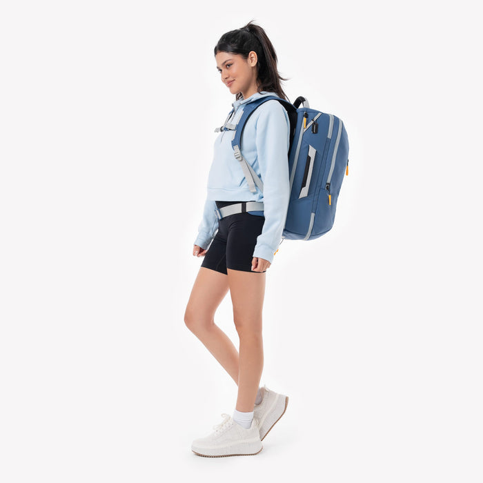 Woman wearing a Sherpani Santiago Seastone Travel Backpack on her back against white backdrop. #color_seastone