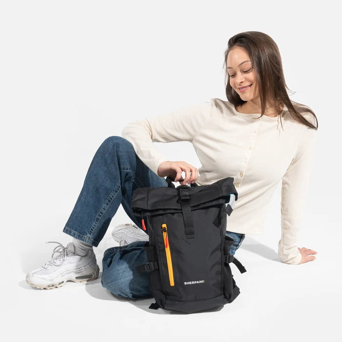 Woman sitting with a Sherpani Sedona Chromatic Black Backpack against white background. #color_chromatic-black