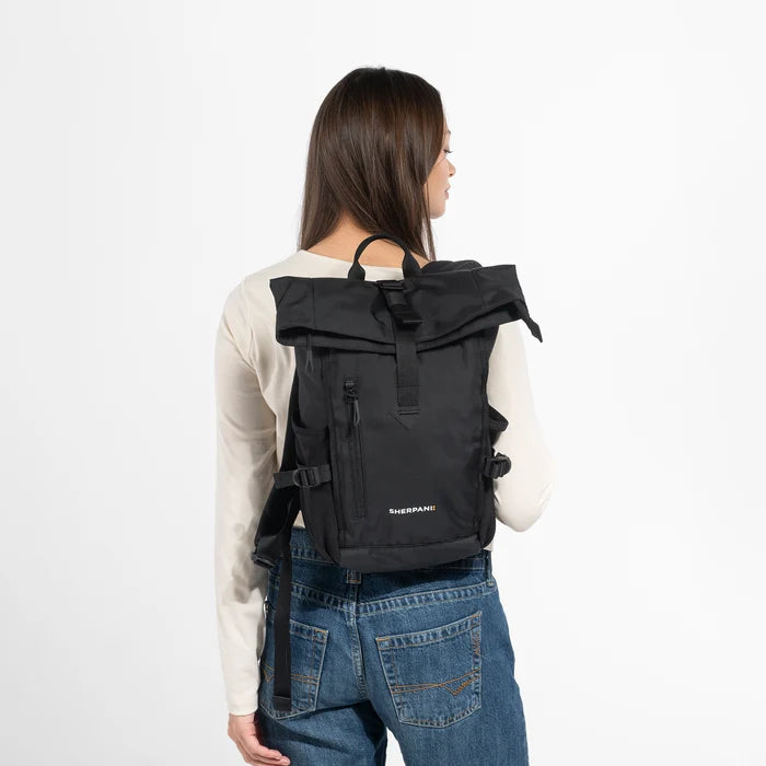 Woman wearing a Sherpani Sedona Raven Black Backpack on her back against white background. #color_raven-black