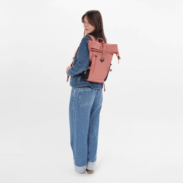 Woman sitting with a Sherpani Sedona Desert Pink Backpack against white background. #color_desert-pink