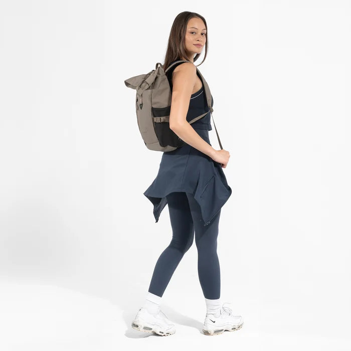 Woman wearing a Sherpani Sedona Dune Backpack on her back against white background. #color_dune-tan